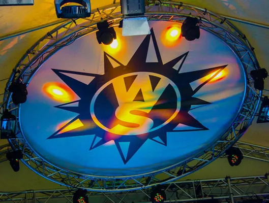 Okrúhla podsvietená plachta s logom festivalu zavesená na konštrukcii nad pódiom