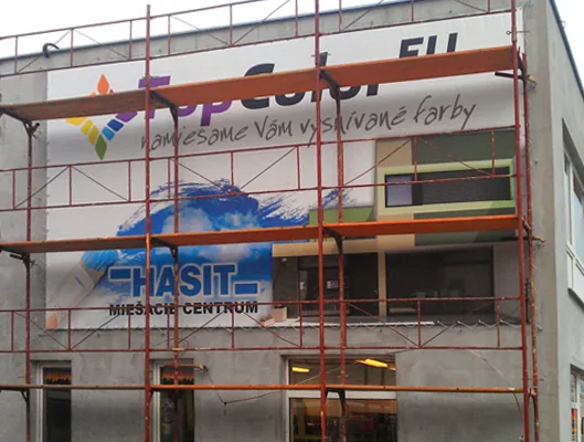 Reklamný banner predajne farieb na fasáde budovy obostavanej lešením