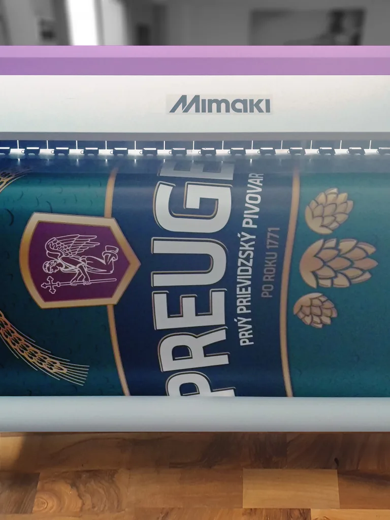 Banner s tmavozelenou grafikou navinutý v tlačiarni Mimaki