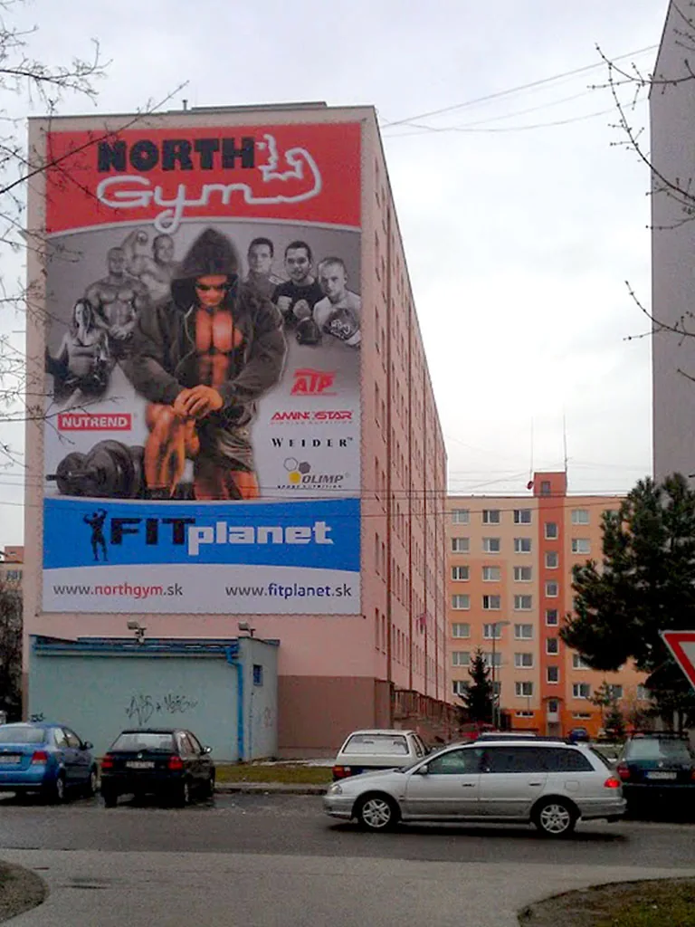 Veľkoplošný reklamný banner fitnescentra na štítovej stene panelového domu
