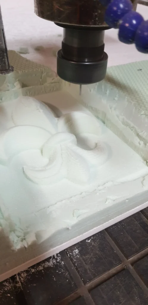 CNC fréza pri frézovaní reliéfu francúzskej ľalie do bieleho materiálu
