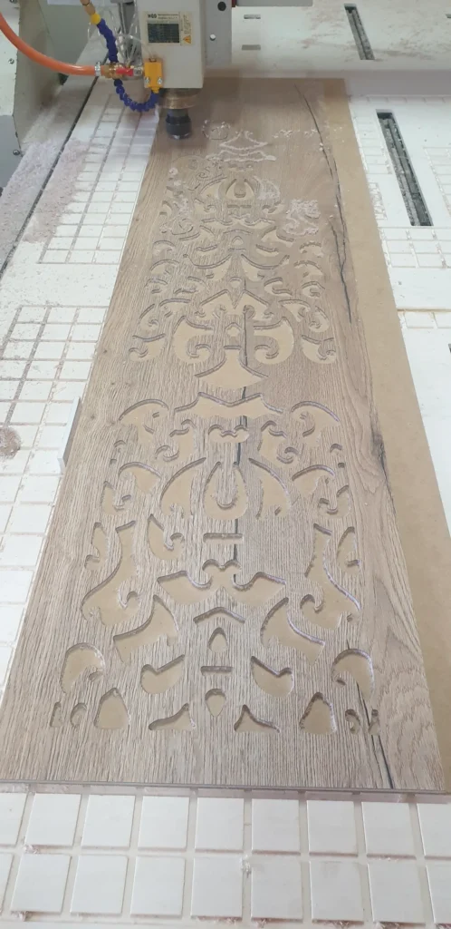 Panel s vyfrézovaným ornamentálnym vzorom na stole frézy