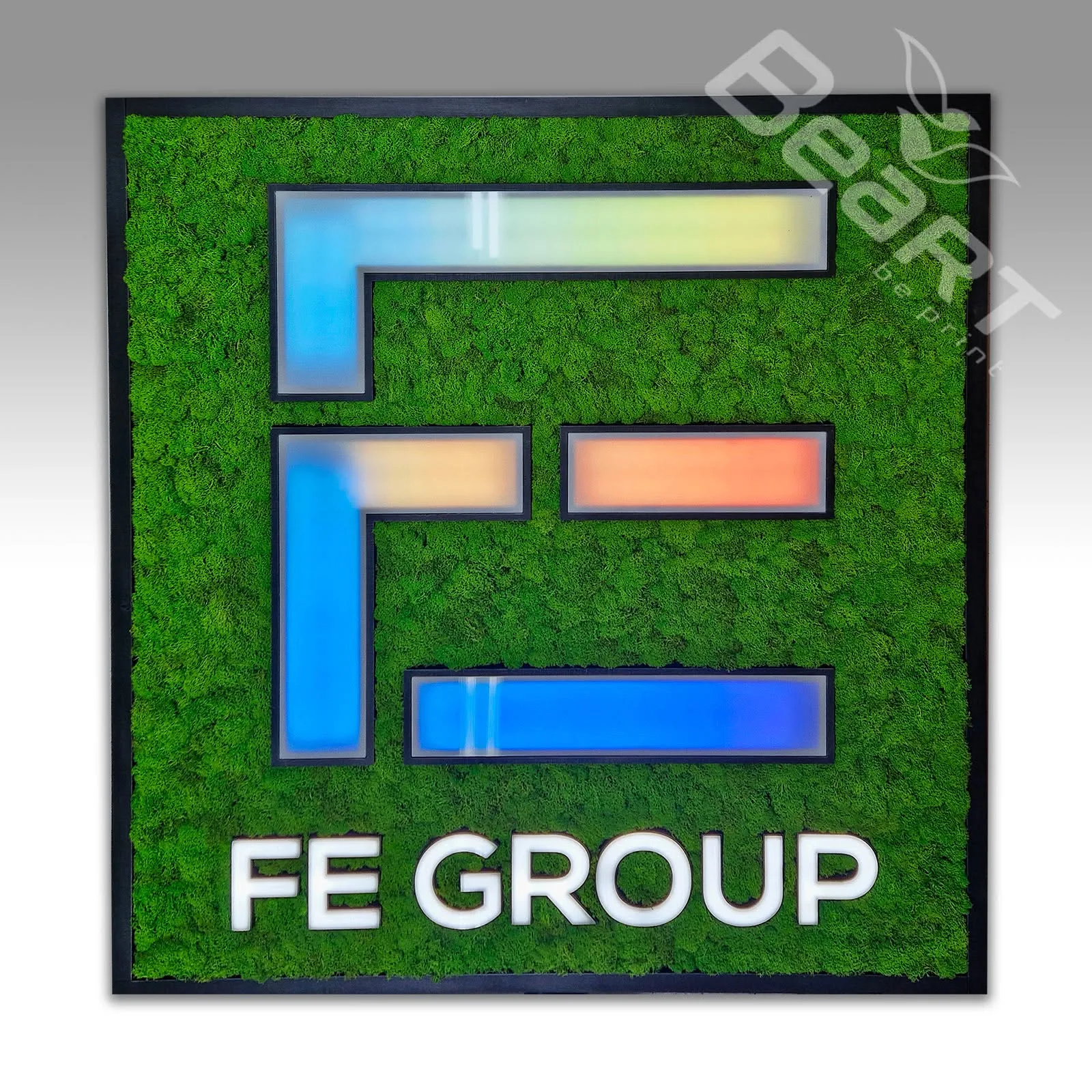 Štvorcový machový obraz s podsvieteným logom FE Group v modro-oranžovej farbe