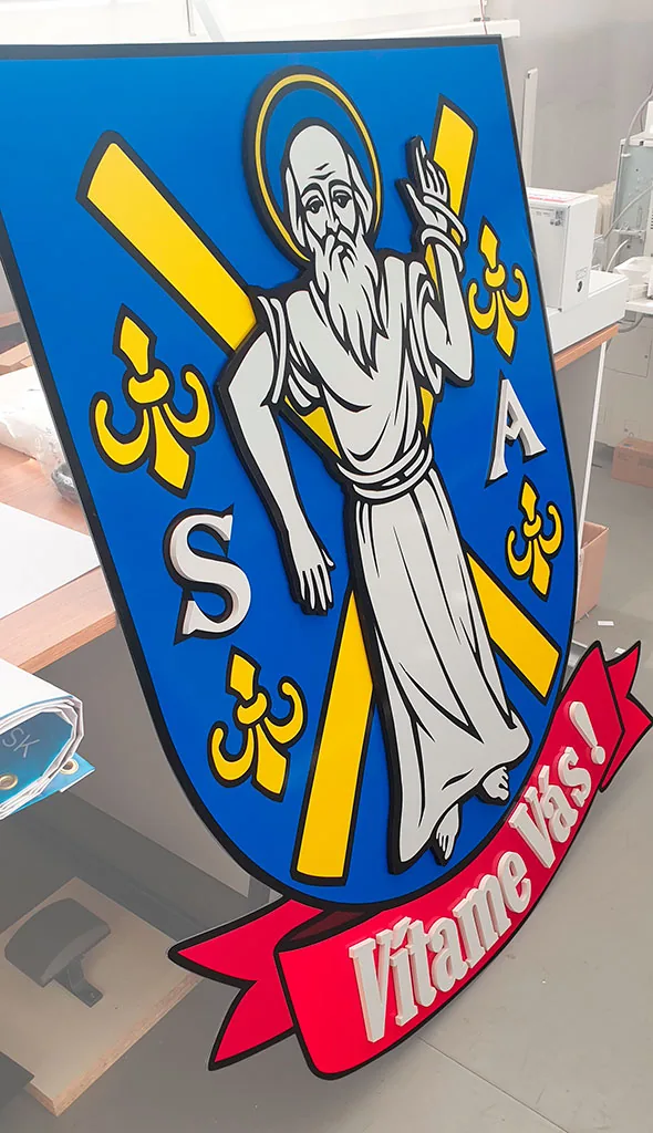 Uvítacia tabuľa obce s erbom a vystúpeným nápisom Vítame Vás v dielni