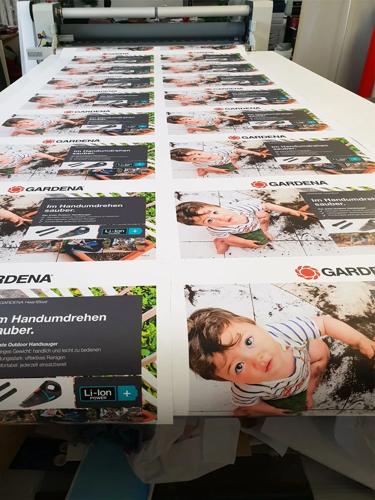 Séria reklamných plagátov po veľkoformátovej tlači na stole laminátora