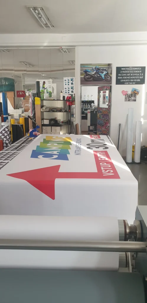 Potlačený banner so smerovou šípkou na navíjacom stroji v dielni